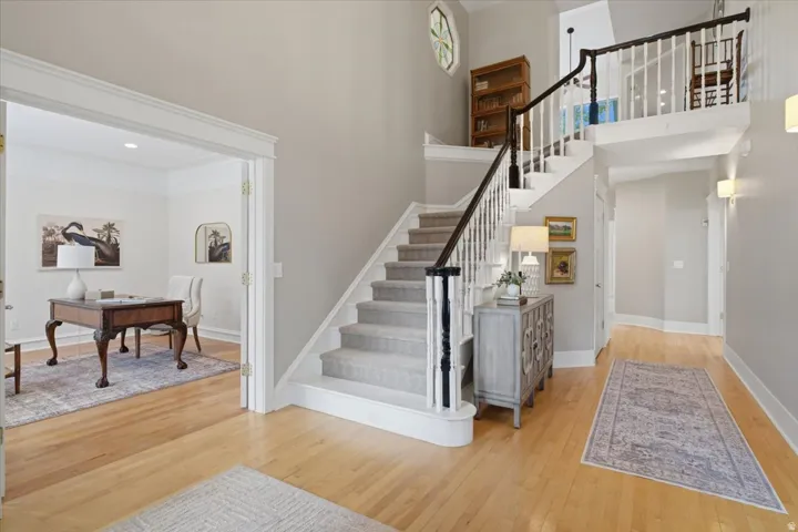 Two-story foyer with a staircase featuring white risers and balusters, dark wood-finish handrail, and carpeted treads
