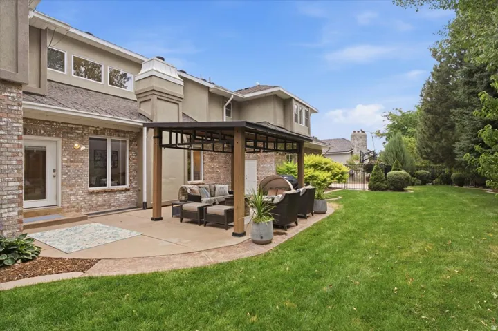 Spacious backyard featuring a large concrete patio, a pergola, and extensive lawn space