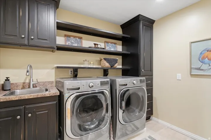 Built-in cabinetry in a dark finish, utility sink with a high-arc faucet, open shelving, and a tall storage cabinet