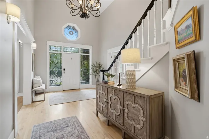 Two-story foyer featuring an ornate chandelier, octagonal transom window, and wood-finish flooring