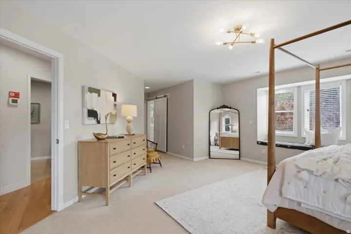 Recessed window seating, flush-mount ceiling light fixture, neutral wall color, carpeted flooring, and a sliding barn door
