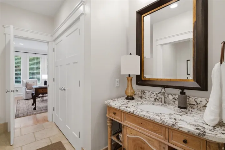 Built-in vanity with a granite countertop, undermount sink, and polished chrome faucet