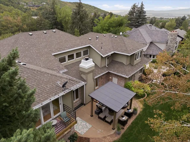 Expansive exterior featuring a covered patio, brick and stucco siding, multiple windows, and a multi-level roofline
