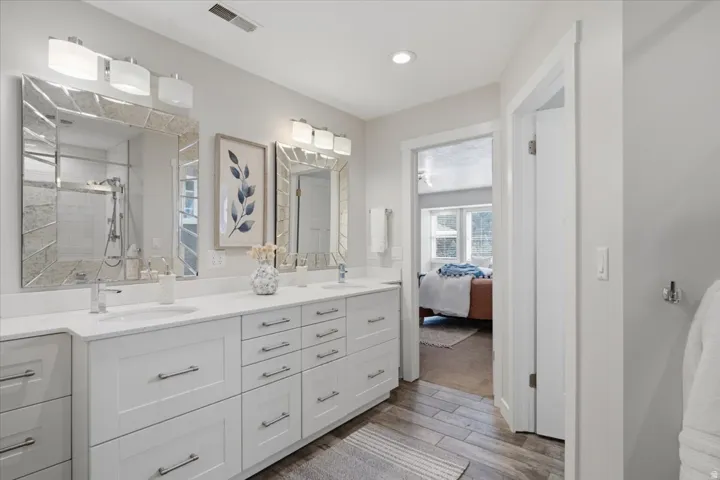 Dual vanity with white cabinetry, polished chrome fixtures, and white countertops