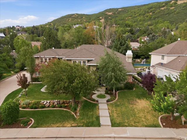 Traditional-style residence with a prominent chimney, a multi-car garage, and a landscaped front yard featuring a concrete walkway