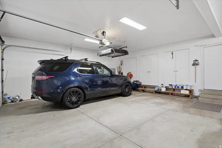 Attached garage with concrete flooring, multiple storage closets, and overhead fluorescent lighting