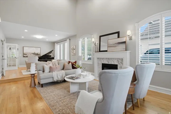 Hardwood flooring, vaulted ceilings, fireplace with stone surround, arched windows with plantation shutters, and recessed lighting