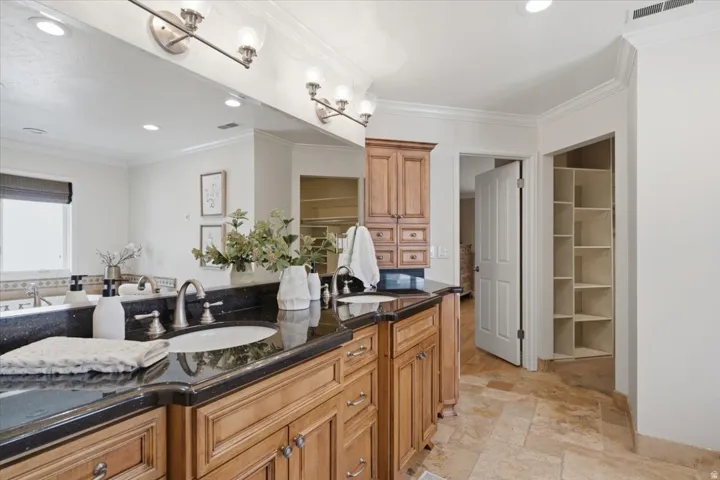Dual vanity with undermount sinks, black countertop, and wood cabinetry