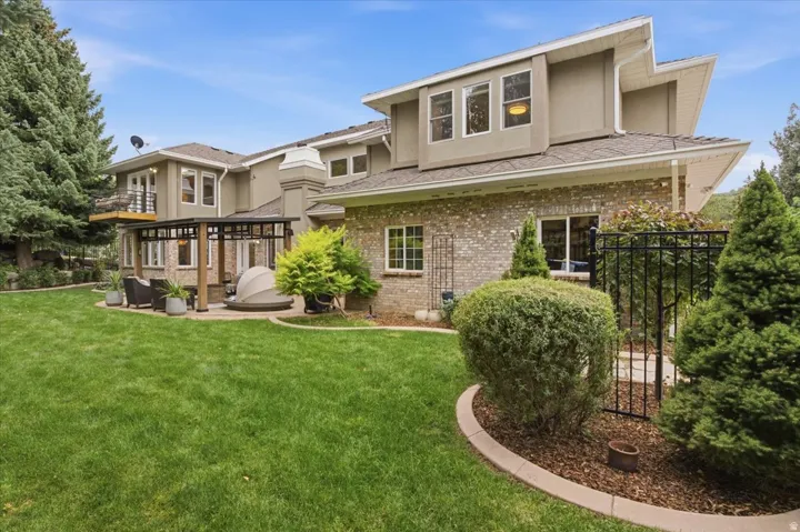 Expansive backyard featuring a stone patio, a multi-level deck, a pergola, and mature landscaping