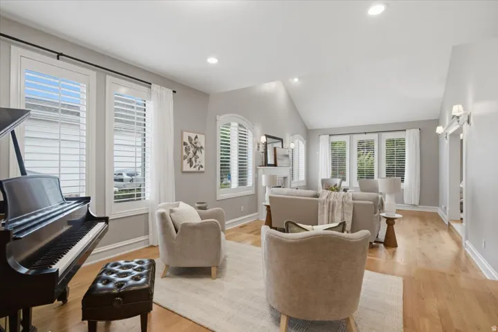 Hardwood flooring, vaulted ceilings, recessed lighting, and multiple windows with plantation shutters