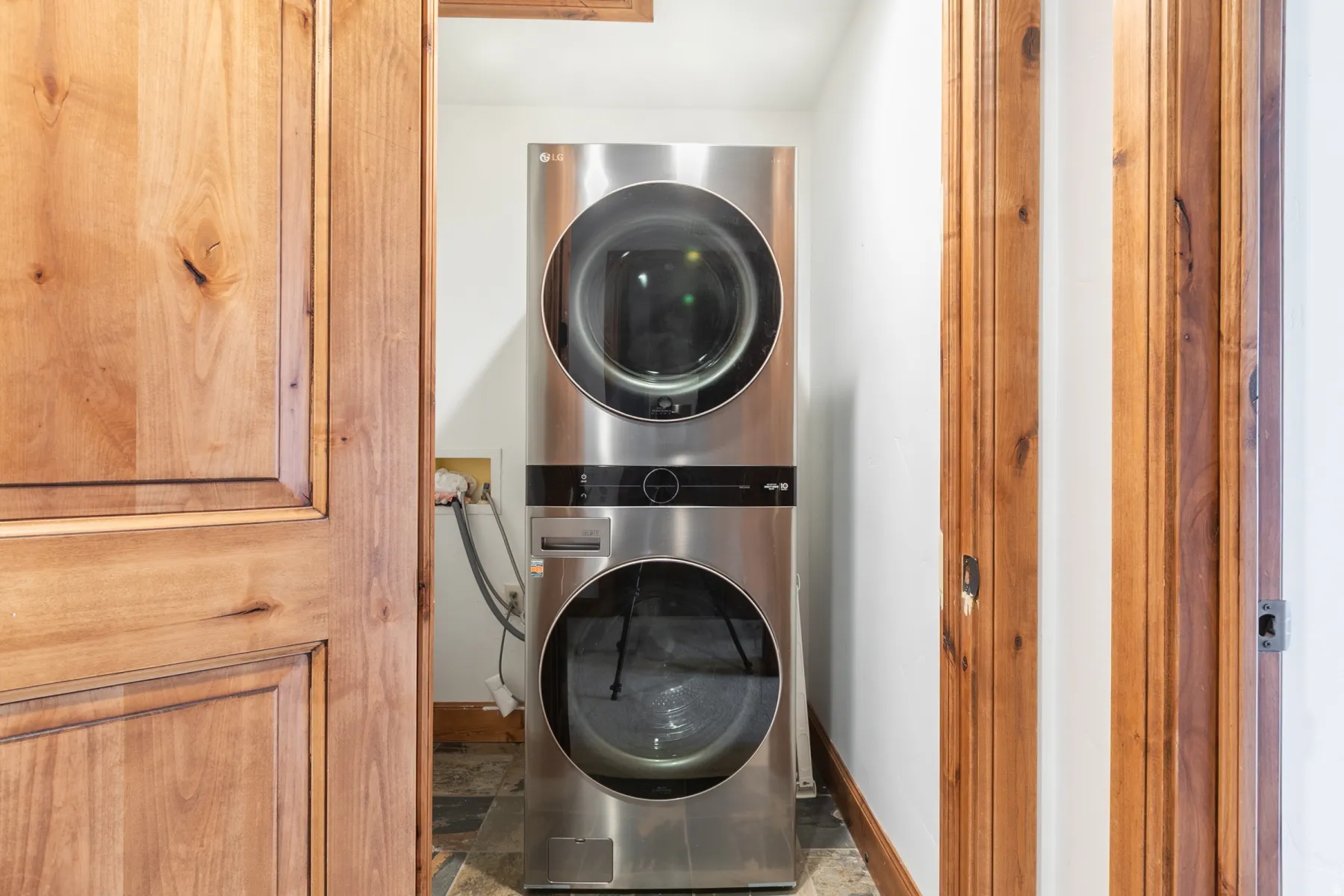 Dedicated laundry room featuring stacked, front-load washer and dryer in stainless steel with modern black trim and control panels