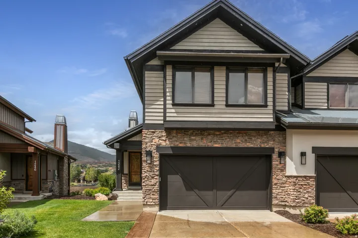Modern two-story residence featuring a striking stone and siding exterior, dark-framed multi-pane windows, and a spacious two-car garage with X-panel detailing