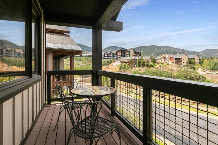 Covered deck with composite wood-finish flooring and metal mesh railing system, overlooking mountain vistas and established residential community