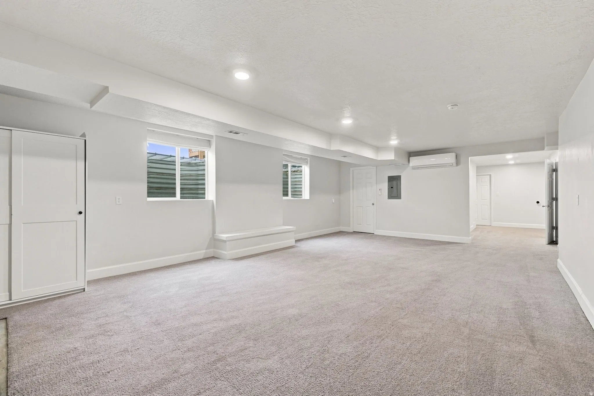 Expansive basement family room with wall-mounted climate control unit.