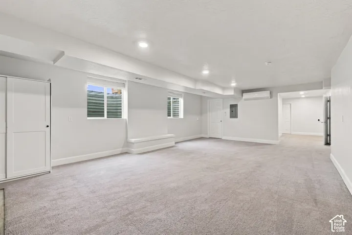 Expansive basement family room with wall-mounted climate control unit.