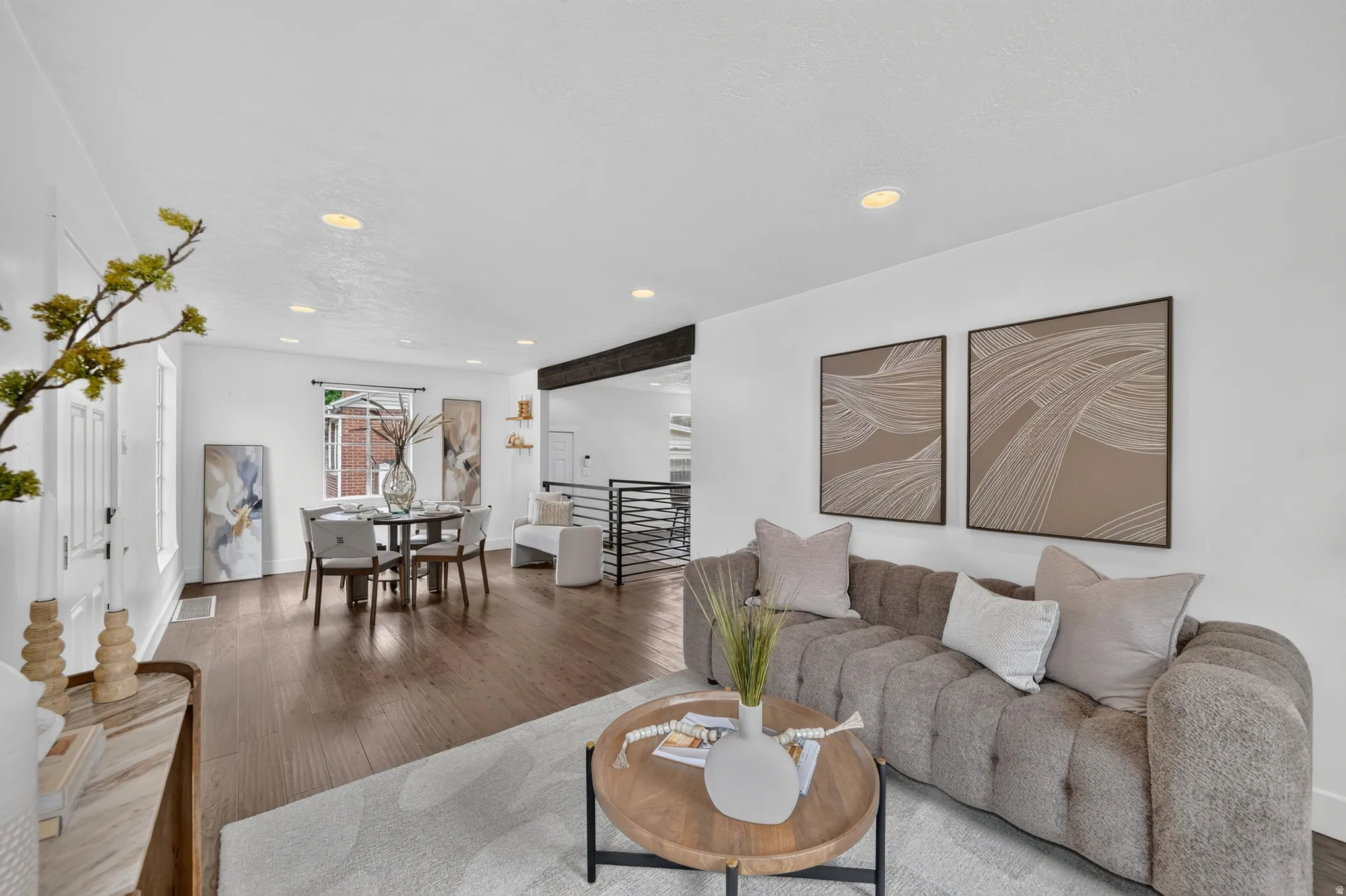 Open-concept living space featuring wood-finish flooring, recessed lighting, and a dining area with a window