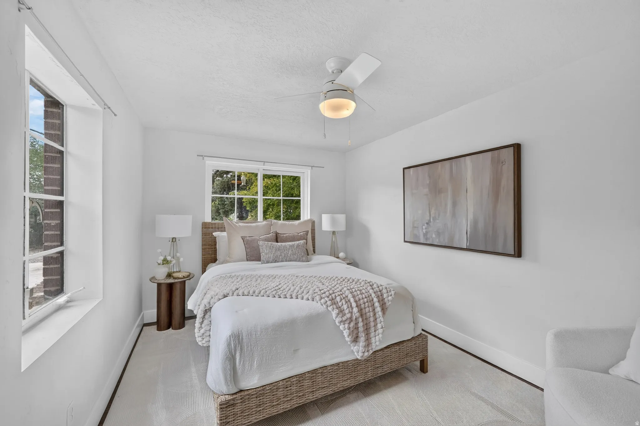 Bright bedroom featuring a wood-finish bed frame, soft white bedding, and woven throw blanket