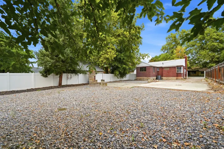Spacious gravel courtyard with mature shade trees and established landscaping, offering ample outdoor space