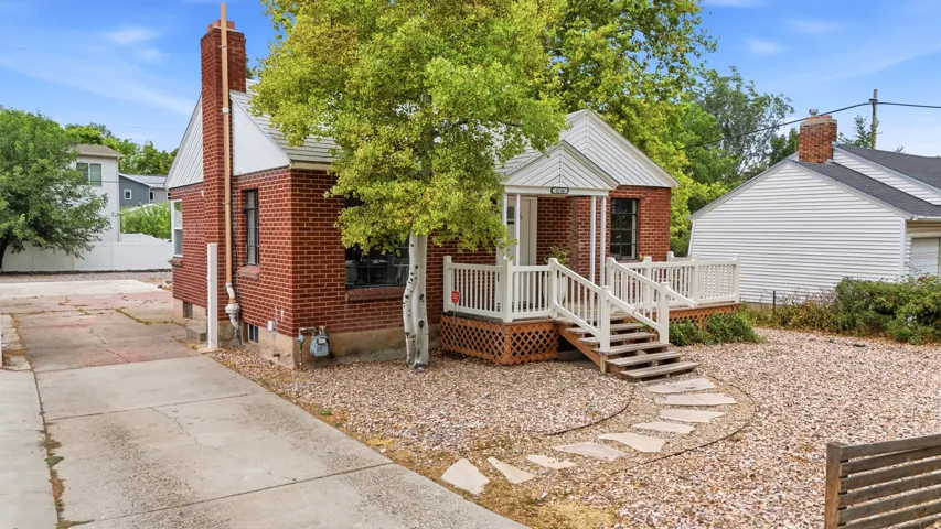 Charming brick cottage with covered front porch, wooden steps, and brick chimney