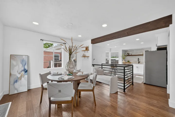 Recessed lighting, wood-finish flooring, wood ceiling beam, white walls, and a black metal railing