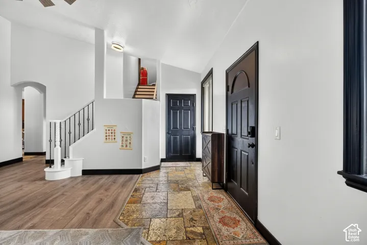 Welcoming foyer showcasing wood-finish flooring, a geometric patterned area rug, and an open staircase with black metal railings