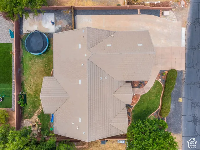 Expansive roof featuring multiple peaks and architectural angles with composite shingle roofing, complemented by mature landscaping including established trees and manicured lawn areas