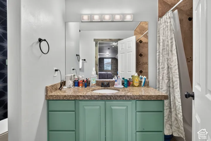Spa-inspired bathroom vanity featuring a granite-topped countertop, dual-sink configuration with chrome fixtures, and soft-close cabinetry in a soft sage finish