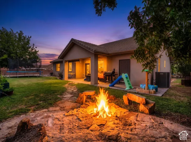 Modern single-story residence with stucco exterior and pitched roof, featuring expansive covered porch with warm ambient lighting