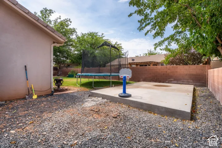 Backyard featuring a concrete pad, gravel hardscaping, and a block wall perimeter