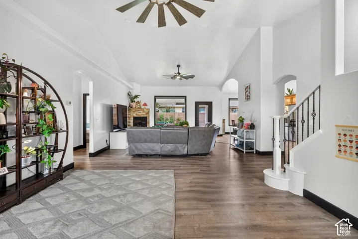 Expansive open-concept living area showcasing soaring vaulted ceilings, wood-finish flooring, and abundant natural light from multiple windows