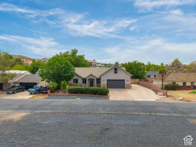 Exterior features a paved driveway, attached garage, and mature landscaping