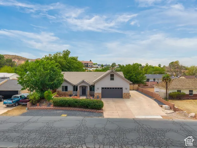 Charming single-story residence featuring a clean stucco exterior with a gabled roofline and dark-finish garage door