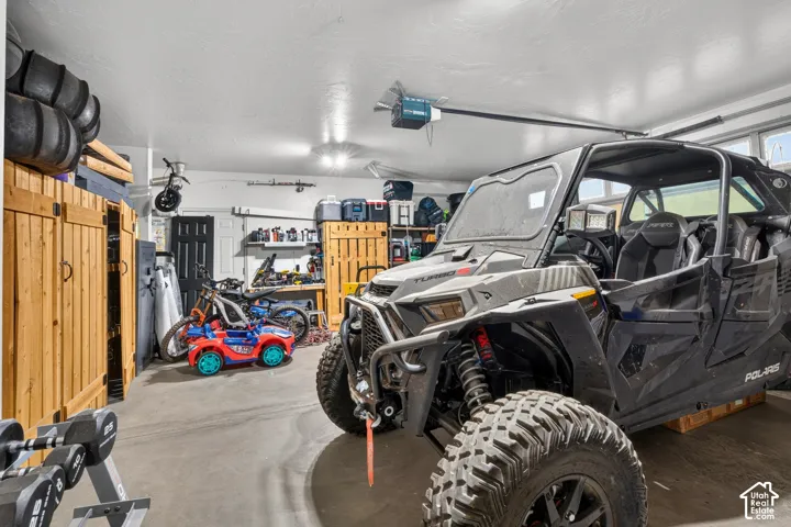 Attached garage with concrete flooring, built-in wooden storage cabinets, and overhead lighting