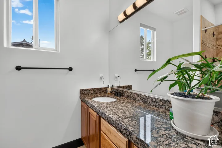 Built-in vanity with wood cabinetry, integrated sink, and granite-finish countertop