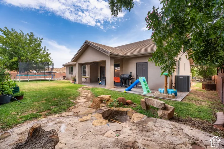 Expansive backyard featuring a stone patio, covered outdoor living space, and a built-in stone fire pit