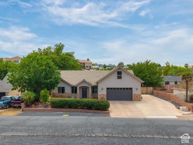 Stucco exterior with stone accenting, a tile roof, and an attached two-car garage