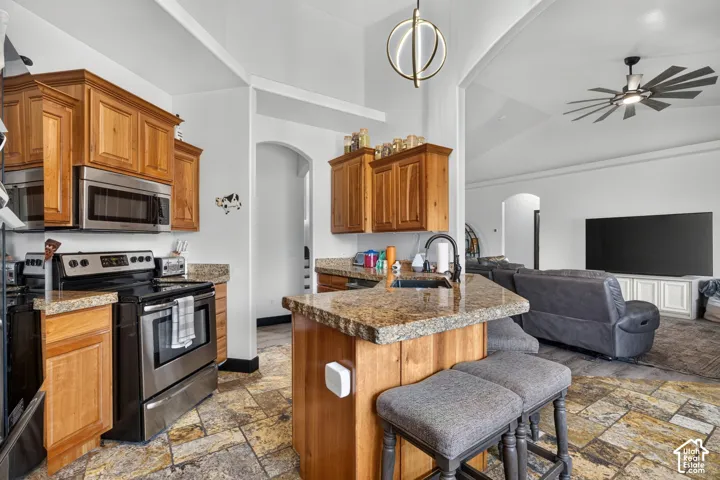 Kitchen featuring wood cabinetry, stainless steel appliances, a stone-finish countertop, and tile flooring