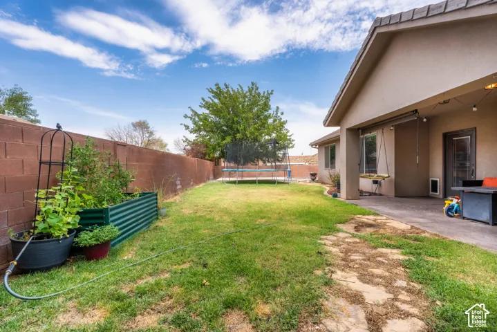 Spacious backyard with mature landscaping, established lawn area, and brick perimeter fencing