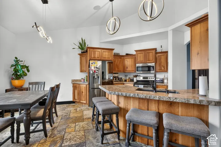 Open-concept kitchen and dining area featuring custom wood cabinetry, stainless steel appliances, granite-style countertops, and a centered island with seating