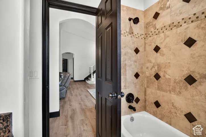 Spa-inspired bathroom showcasing travertine tile walls with decorative black diamond inlay pattern, white soaking tub, and black plumbing fixtures