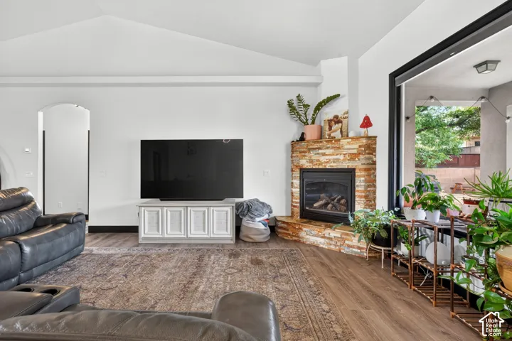Spacious open-concept living area featuring wood-finish flooring, a brick fireplace with gas insert, built-in media console with white cabinetry, and abundant natural light from large sliding glass doors