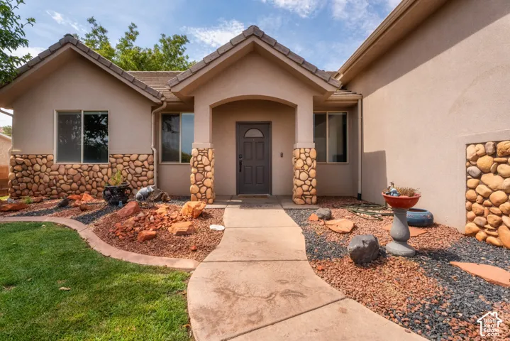 Welcoming front entry with arched doorway and dark wood door, flanked by decorative stacked stone accents