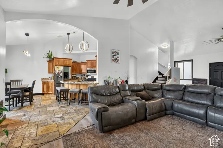 Open-concept living area featuring a curved sectional seating arrangement, wood-finish flooring with geometric inlay detailing, and pendant lighting