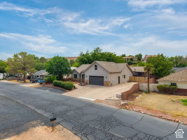 Newly constructed residence featuring a modern stucco exterior with stone accents, three-car garage, and professionally finished driveway