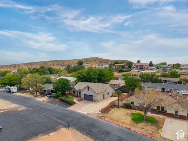 Aerial view showcasing a substantial residence with tan stucco exterior and dark roof, positioned on a generous lot with mature landscaping