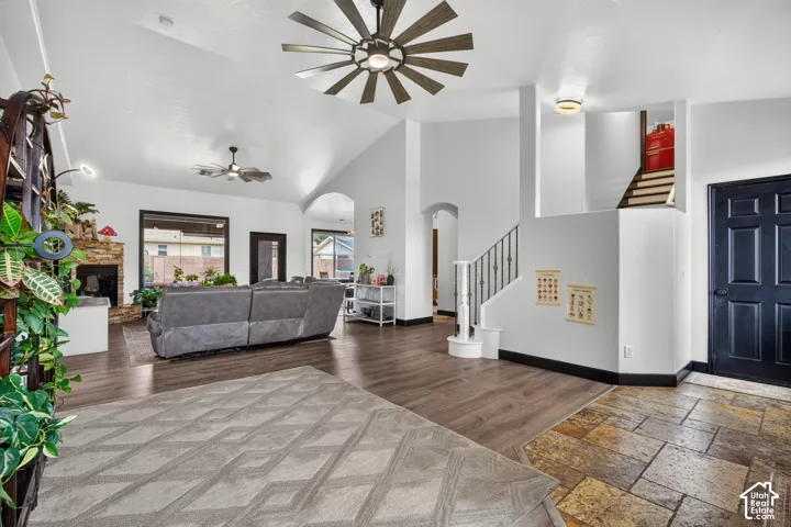 Vaulted ceilings, wood-finish flooring, stone tile entry, stone fireplace, and a staircase with wrought iron balusters