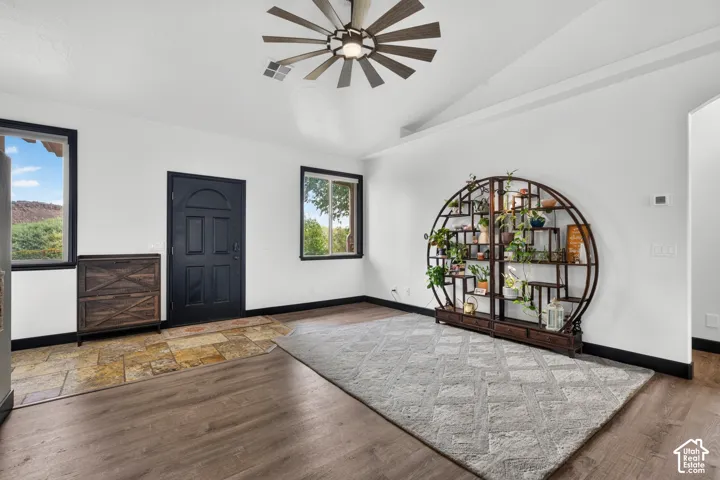 Spacious entry foyer featuring hardwood flooring, a dark six-panel entry door, and a modern ceiling fan with brushed metal finish