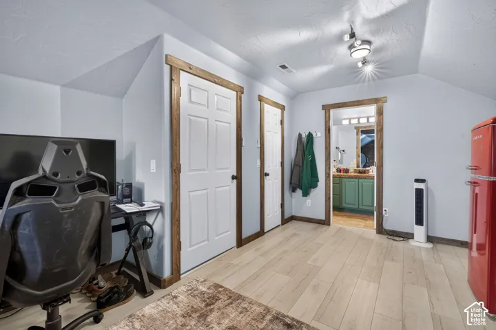 Bright upper-level room featuring sloped ceilings, wood-finish flooring, and multiple closet doors with wood trim