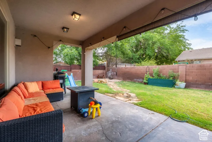 Covered patio with concrete flooring and overhead beams, overlooking a spacious fenced backyard with mature trees and established lawn