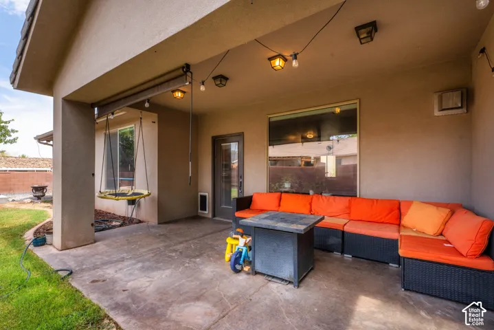 Covered patio with a concrete surface, featuring an exterior door, a large window, and wall-mounted lighting fixtures